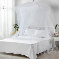 a white canopy bed with two pillows on it