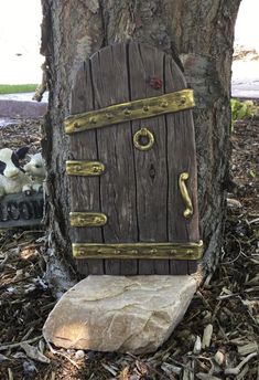 a wooden door sitting on top of a rock next to a tree