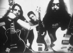 three men with long hair and beards are posing for a photo while holding guitars