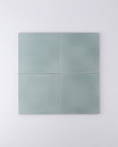 a white wall with four square tiles on the bottom and one in the middle that is light blue