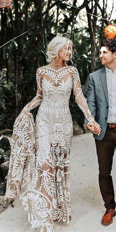 a man and woman holding hands while walking through the woods