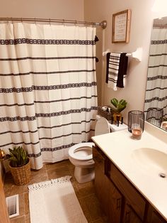 a white toilet sitting next to a bath tub in a bathroom under a shower curtain