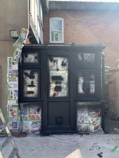 an outdoor newspaper dispenser in front of a brick building covered in newspapers