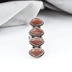 METAL DETAILS : ✦ Metal Type : 925 Sterling Silver ✦ Stamp : 925 ✦ Full Silver Back GEMSTONE DETAILS :  ✦ Gemstone :  Chocolate Moonstone ✦ Gemstone Type : Natural ✦ Gemstone Size : (Centre)-8x14 MM, (Side)-8x14 MM ✦ Gemstone Setting : Cabochon RING DETAILS : ✦ Ring Size : Adjustable (US 6MM TO US 11 MM) ✦ Ring Measurement : Length- 47 MM, Breadth- 18 MM ✦ Total Ring Weight :15 GRAMS This unique, one-of-a-kind ring, meticulously handmade by our talented artisans, is truly a gem that will never b Brown Sterling Silver Cabochon Ring, Brown Sterling Silver Ring With Cabochon, Sterling Silver Rings With Brown Natural Stones, Brown Sterling Silver Rings With Natural Stones, Adjustable Brown Sterling Silver Ring, Brown Gemstone Ring In Sterling Silver, Brown Gemstone Rings In Sterling Silver, Brown Gemstone Sterling Silver Rings, Brown Natural Stone Ring