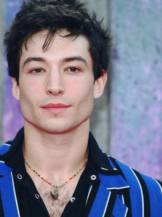 a close up of a person wearing a blue and black shirt with a necklace on