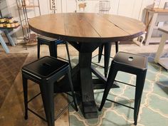 a wooden table and four stools in a room with other items on the floor