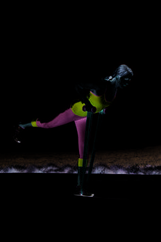 a woman in neon colored clothing leaning on a pole with her leg up and legs crossed