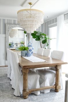 a dining room table with white chairs and a chandelier hanging from the ceiling