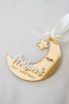 a gold plated christmas ornament hanging from a white ribbon