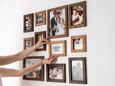 a woman is placing pictures on the wall with her hands and holding them in place