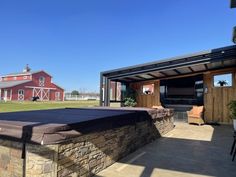 an outdoor hot tub sitting on top of a stone wall next to a red barn