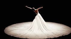 a woman in a white dress standing on top of a black floor with her arms outstretched