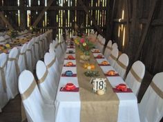 a long table set up with white chairs and burlocked linens for an event