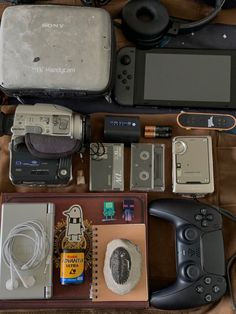 an assortment of electronic devices and accessories laid out on a table with wires, cords, books, and other items