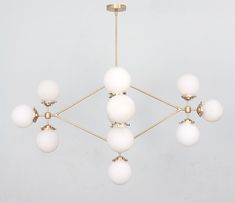 a chandelier with six white balls hanging from it's center point,