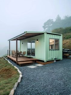 a green shipping container sitting on top of a gravel covered hillside next to a picnic table