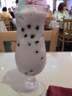 a tall glass filled with liquid sitting on top of a white table next to a red napkin