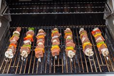 several skewered meats are cooking on the grill