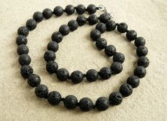 Lava Rock necklace 8mm black lava rock bead necklaces for men Volcanic lava black jewelry for husband hand knotted black lava rock necklace This beautiful hand knotted necklace made with 8mm black lava rock beads. This necklace has knots between each bead. You can choose the lenght of a necklace. Your necklace will be made and sent within 2 work days.   International delivery can take from 7 days up to 5 weeks.   All purchases will be sent by Ukrainian airmail with a tracking number attached. Pl Spiritual Single Strand Black Jewelry, Black Beads Lava Stone Jewelry, Black Beaded Lava Stone Jewelry, Lava Stone Jewelry With Natural Round Beads, Black Lava Stone Jewelry With Round Beads, Round Lava Stone Beads Jewelry, Natural Lava Stone Round Beads Jewelry, Lava Stone Jewelry With Round Natural Stones, Elegant Black Lava Stone Jewelry