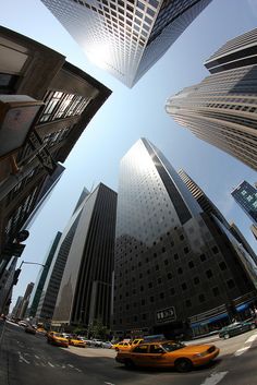 an intersection with taxi cabs and tall buildings