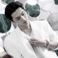 a man in a white suit and gold bracelets