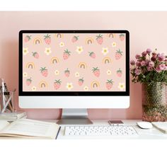 a desktop computer sitting on top of a desk next to a vase with flowers and books