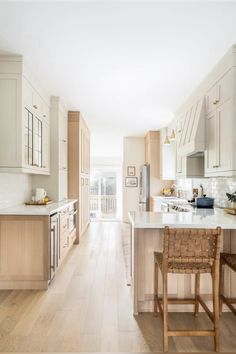 a large kitchen with white cabinets and wood flooring on the walls, along with an island in the middle