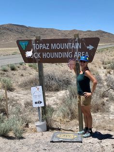 two women standing next to a sign in the desert