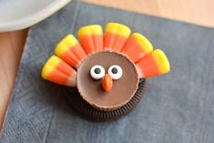 a cupcake decorated like a turkey on top of a blue napkin with candy eyes