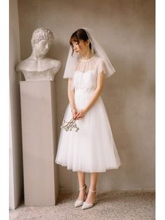 a woman in a white dress standing next to a busturine wearing a veil