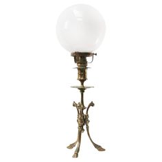 an antique brass table lamp with a white glass ball on it's top and base