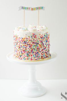 a birthday cake with colorful sprinkles and a happy birthday sign on top