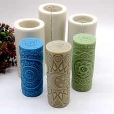 four different colored vases sitting next to each other on a white surface with flowers in the background