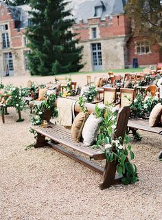 a wooden bench sitting in front of a bunch of chairs on top of a gravel field