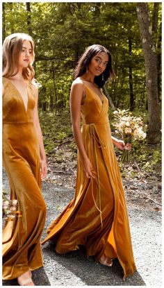 two women in long dresses walk down the road together, one wearing a yellow dress