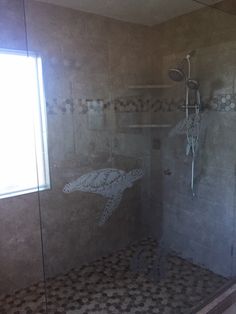 a bathroom with a walk in shower sitting next to a window and tiled flooring