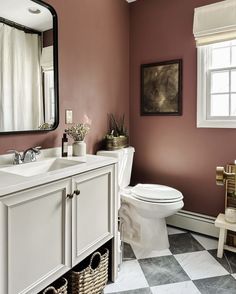 a white toilet sitting next to a sink in a bathroom under a mirror and a window