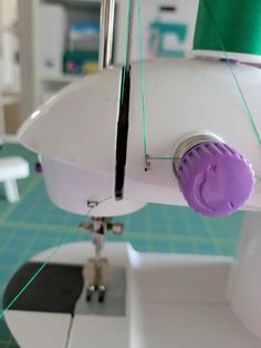 the sewing machine is being worked on by someone using scissors to sew something purple