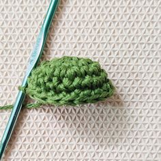 a green crochet hook on top of a piece of cloth