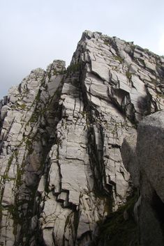 the top of a rock formation with moss growing on it's sides and rocks below