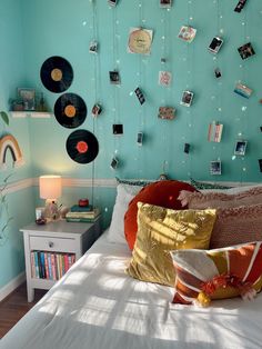 a bed room with a neatly made bed and lots of pictures on the wall above it