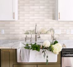 a kitchen sink with white flowers and greenery