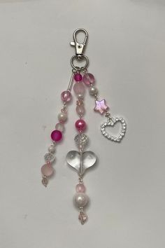 a key chain with charms attached to it on a white surface, including a heart