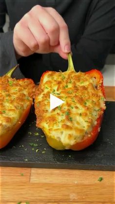 two stuffed peppers being cut into pieces on a cutting board with a person in the background