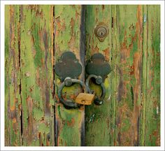 an old wooden door with a lock and padlock on the handle is painted green