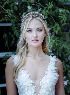 a beautiful blonde woman wearing a white wedding dress and a tiara with flowers on it