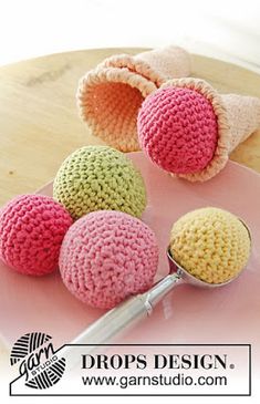 four crocheted balls on a pink plate with a spoon