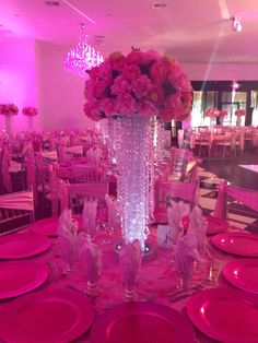 a tall vase filled with pink flowers sitting on top of a table covered in plates