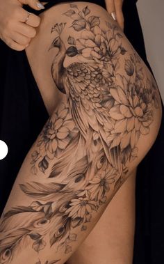 a woman's thigh with flowers and a bird tattoo on her leg, while she is showing off her tattoos