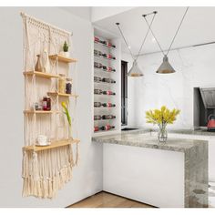 a white kitchen with macrame hanging from the wall and shelves on the wall